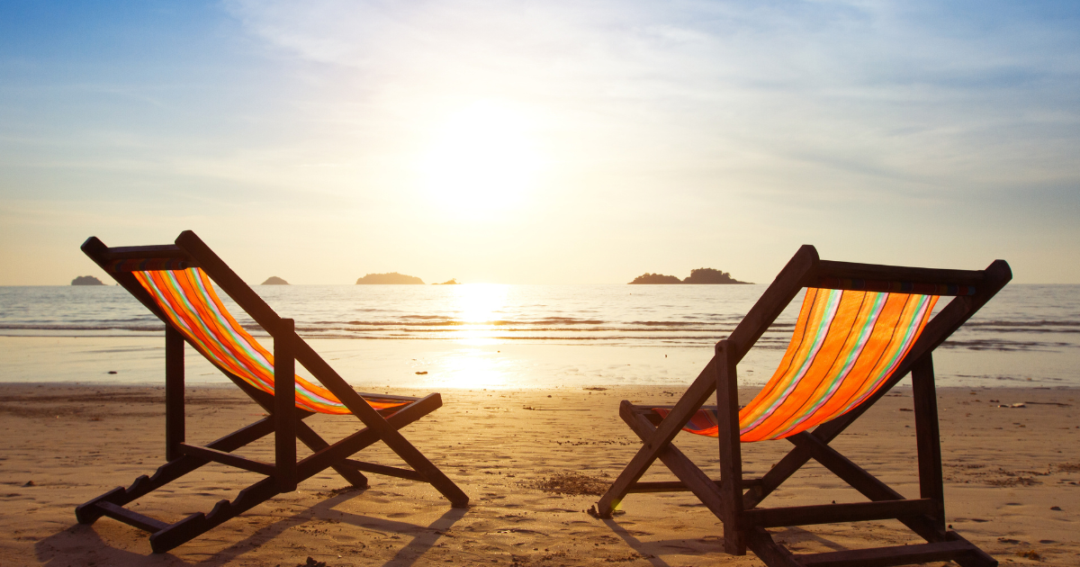 Beach chairs on a beach with the sun shining.